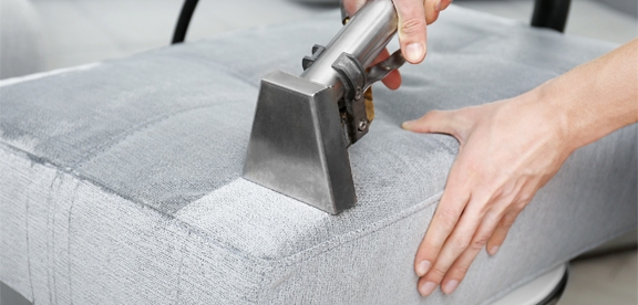 This image shows a vacuum being used to clean a sofa.
