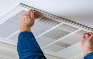 This image shows a man removing an air duct cover.